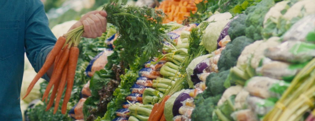 customer holding carrots in front of wet rack